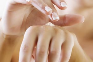 closeup of female hands applying hand cream